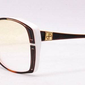 Peut inclure: Lunettes de vue en plastique blanc et marron avec un logo dor&eacute; "JP Paris".