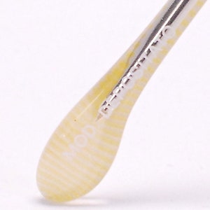 May include: Close-up of a white and yellow striped temple tip of a pair of eyeglasses. The temple tip has the word "MOD" printed on it.