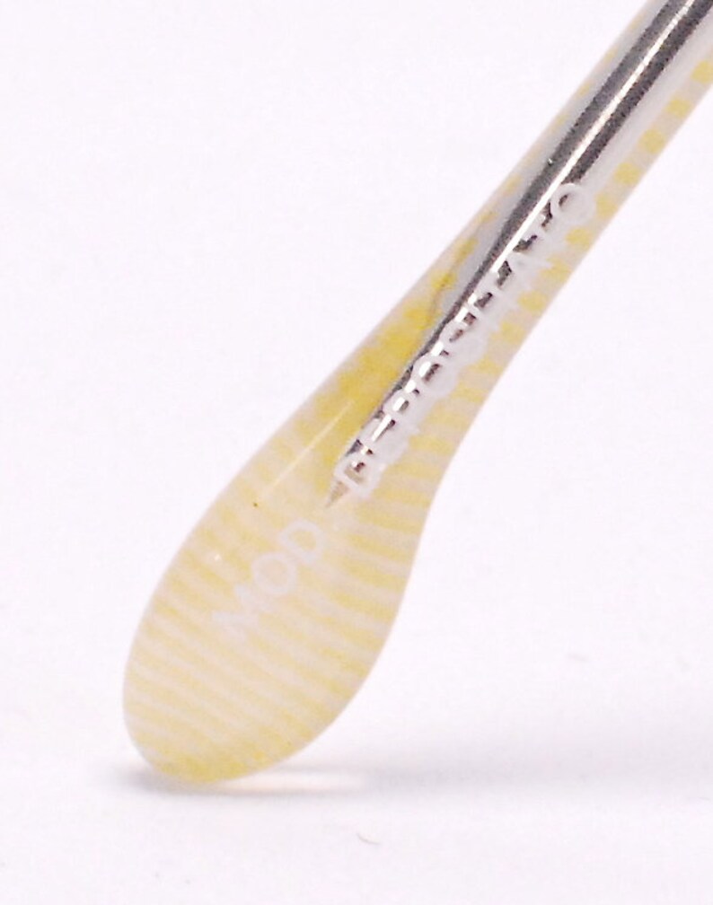 May include: Close-up of a white and yellow striped temple tip of a pair of eyeglasses. The temple tip has the word "MOD" printed on it.