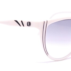 May include: White cat-eye sunglasses with black accents and a gradient lens.