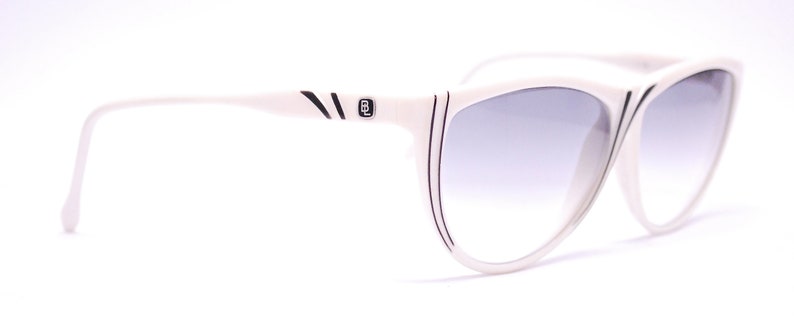 May include: White cat-eye sunglasses with black accents and a gradient lens.