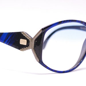 Op de afbeelding: Blauw en zwart gepatroneerde bril met blauwe getinte glazen.