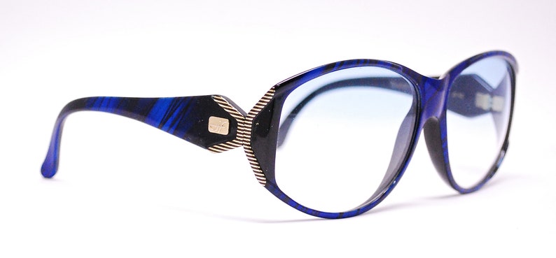 Op de afbeelding: Blauw en zwart gepatroneerde bril met blauwe getinte glazen.