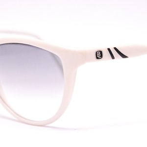 May include: White cat-eye sunglasses with black accents and a gradient lens.