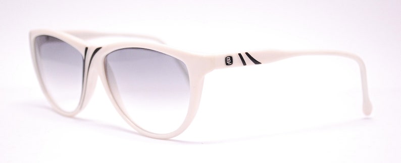 May include: White cat-eye sunglasses with black accents and a gradient lens.