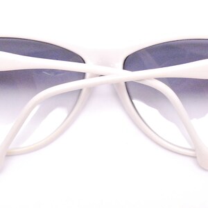 May include: White cat-eye sunglasses with black accents and a gradient lens.
