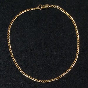 May include: A gold chain necklace with a lobster clasp.