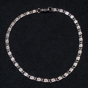 May include: A silver chain necklace with a delicate, intricate design. The chain is made of small, linked loops that create a unique and stylish look.