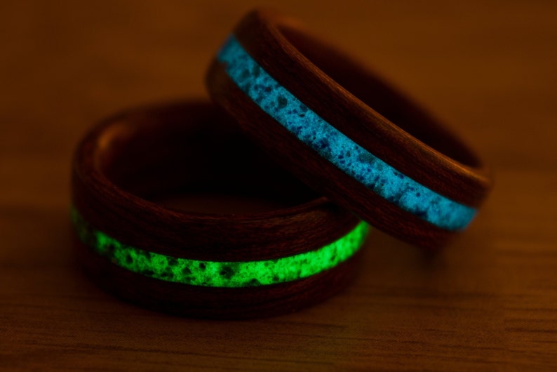 Puede incluir: Dos anillos de madera con una incrustaci&oacute;n verde y azul brillante. Los anillos est&aacute;n apilados uno encima del otro.