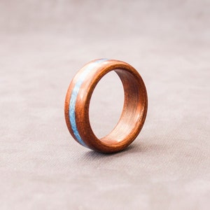 Puede incluir: Un anillo de madera con una incrustaci&oacute;n azul. El anillo es marr&oacute;n y tiene un acabado liso.
