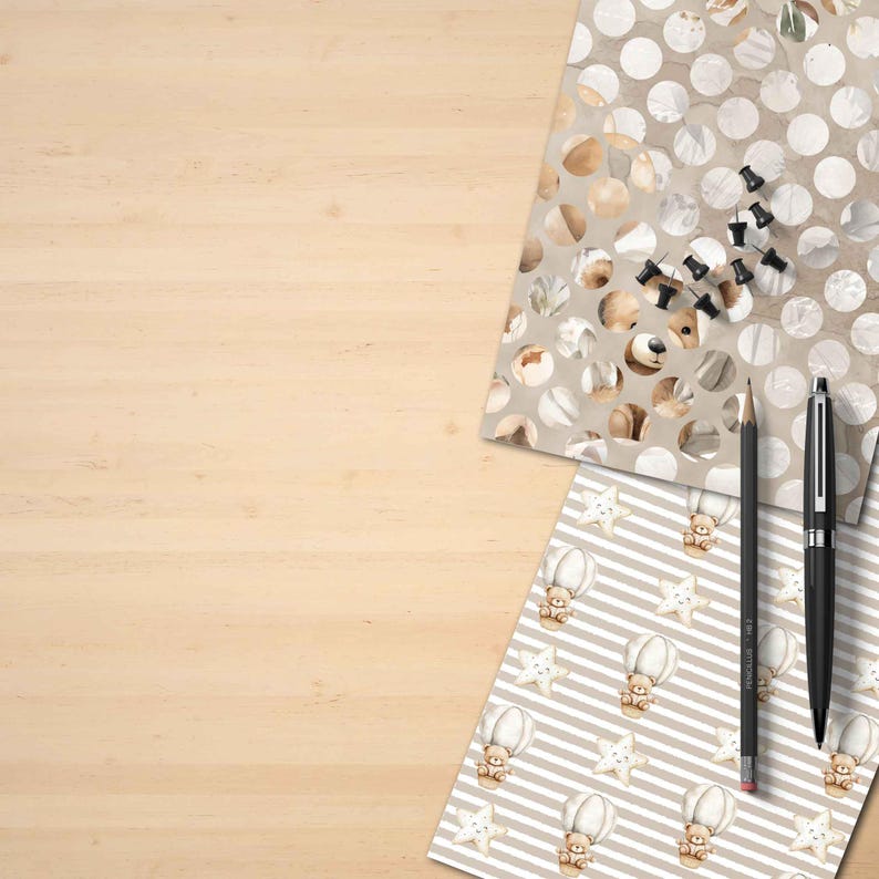 Puede incluir: Un escritorio de madera con art&iacute;culos de papeler&iacute;a y papel estampado. El papel presenta osos de peluche, estrellas y globos aerost&aacute;ticos. Un l&aacute;piz negro, un bol&iacute;grafo negro y chinchetas negras tambi&eacute;n est&aacute;n en el escritorio.