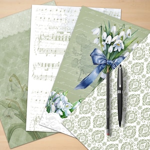 Puede incluir: Cuatro hojas de papel con diferentes dise&ntilde;os. Una hoja tiene una partitura musical, otra tiene un patr&oacute;n floral con un ramo de campanillas blancas atadas con una cinta azul, otra tiene un patr&oacute;n damasco verde y blanco, y la &uacute;ltima hoja tiene un patr&oacute;n floral verde y blanco con texto escrito a mano. Dos l&aacute;pices est&aacute;n sobre las hojas.