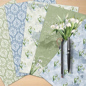 Puede incluir: Cinco hojas de papel decorativo con una variedad de patrones. Una hoja presenta un patr&oacute;n floral blanco sobre un fondo azul claro. Otra hoja presenta un patr&oacute;n floral blanco sobre un fondo verde claro. Las tres hojas restantes presentan un patr&oacute;n floral blanco sobre un fondo verde claro con acentos de acuarela.
