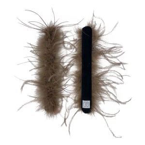 May include: Two brown feather boas and a black velvet headband. The fluffy boas have a soft texture. The rectangular headband has a small white tag with text. The items are isolated on a white background.