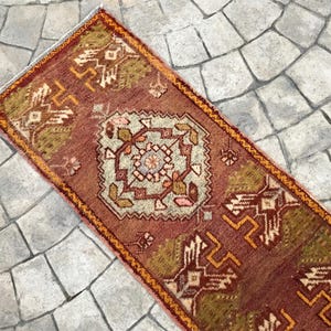 May include: A red, orange, and green patterned rug with a geometric design. The rug is rectangular and has a fringe border.