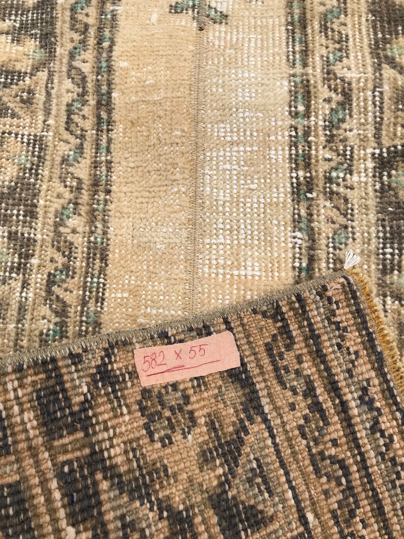 Pu&ograve; includere: Primo piano di un tappeto con un motivo marrone e beige. Il tappeto ha un'etichetta che recita "582 x 55".