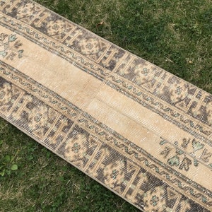 Pu&ograve; includere: Un tappeto da runner vintage con sfondo beige e motivi geometrici marroni e verdi. Il tappeto ha un aspetto vissuto ed &egrave; perfetto per aggiungere un tocco di stile boh&eacute;mien alla tua casa.
