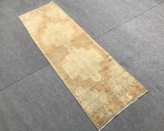 May include: A beige and brown runner rug with a geometric pattern. The rug has a faded, vintage look.