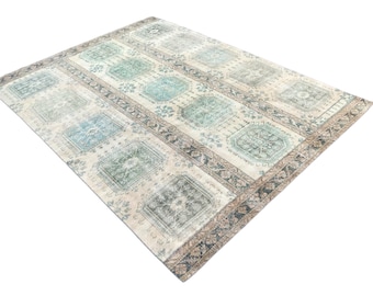 May include: An area rug with a rectangular design. The rug features a cream-colored background with a repeating pattern of rectangular shapes in shades of blue and green. The border is a darker color with floral patterns.