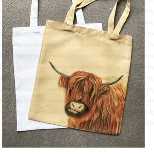 May include: Two tote bags, one white and one beige. The beige bag has a printed image of a Highland cow with brown and red fur. The text "Jules Kenworthy Art" is repeated on the beige bag.