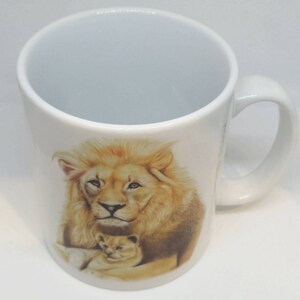 May include: White ceramic mug with a brown and white image of a lion and a lion cub. The lion is looking directly at the viewer.