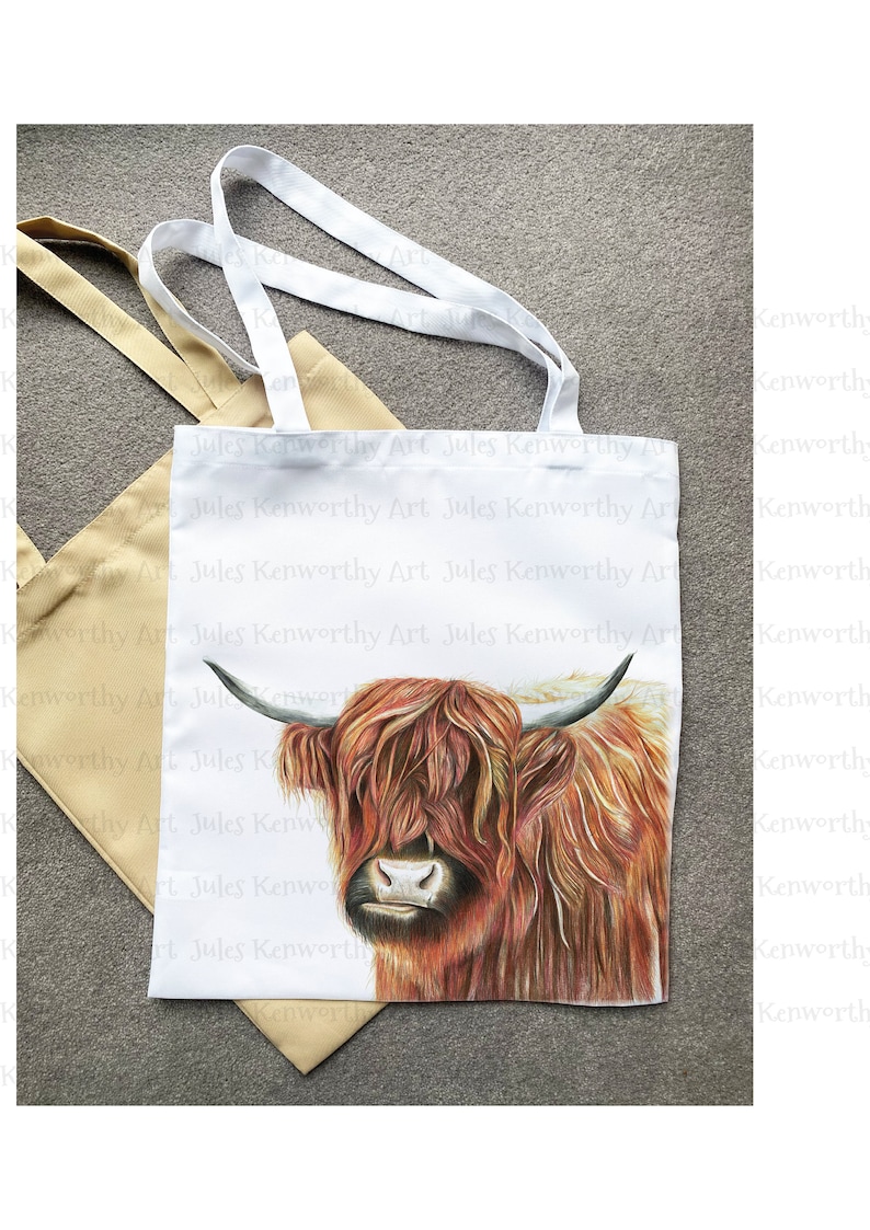 May include: A white tote bag with a brown and white Highland cow illustration. The bag has the text "Jules Kenworthy Art" repeated on the front.