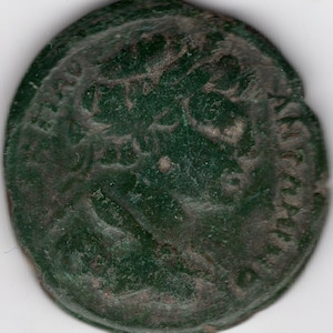 May include: A green Roman coin with a portrait of a person on one side. The coin is worn and has a patina.