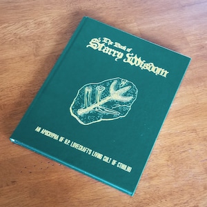 May include: A green book with the title "The Book of Starry Wisdom" in gold lettering. The book is an apocrypha of H.P. Lovecraft's Living Cult of Cthulhu.
