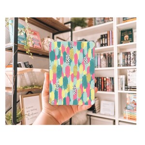 May include: A colorful abstract pattern with pink, yellow, blue, and green brushstrokes and black and white polka dots on a white background. The pattern is on a phone case.