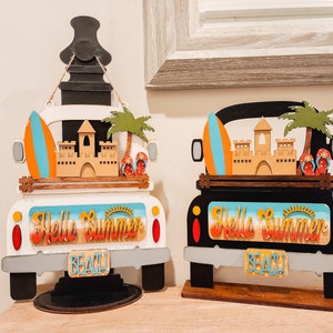 May include: Two wooden truck-shaped signs, one white and one black, with beach-themed decorations. Each features a surfboard, sandcastle, palm tree, and flip-flops. The signs read "Hello Summer" and "Beach".