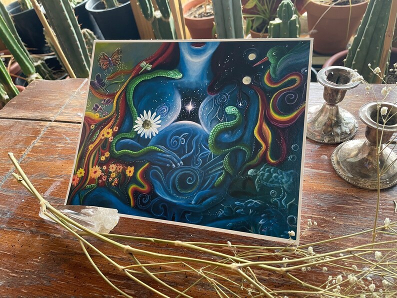 May include: A colorful abstract painting with a blue, green, and red color scheme. The painting features a woman's body with a snake wrapped around her, a hummingbird, and a daisy. The background is a dark blue with stars and swirls.