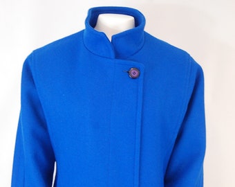 May include: A long, cobalt blue coat with a mandarin collar and a single button fastening. The coat has a simple, elegant design.