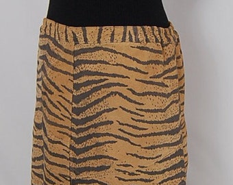 May include: A black turtleneck sweater with a brown and black striped skirt. The skirt has a tiger print pattern.