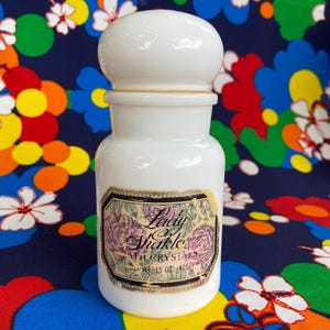 Puede incluir: Tarro de vidrio blanco con tapa blanca y una etiqueta que dice "Lady Shackle Bath Crystals" con un peso de 1,5 oz (42,5 g).