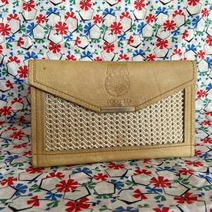 May include: A tan leather wallet with a woven pattern on the front. The wallet has a flap closure and a metal clasp. The text "LOCAL 311" is embossed on the front of the wallet.
