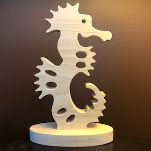 以下が含まれることがあります： 詳細なデザインの、木製のタツノオトシゴの彫刻。タツノオトシゴは木製の台座の上に立っています。