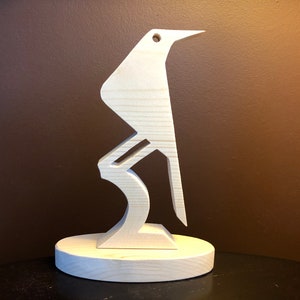 May include: A wooden bird sculpture with a simple, abstract design. The bird is standing on a round base.