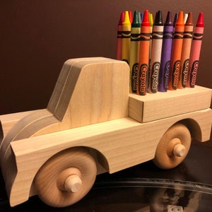 May include: A wooden toy truck with a bed full of Crayola crayons in various colors, including red, orange, yellow, green, blue, purple, brown, and pink.