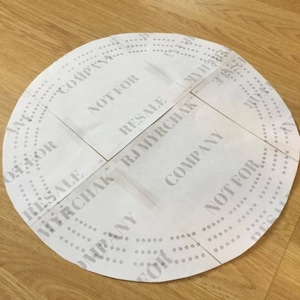 May include: A circular paper product with the text "NOT FOR RESALE" and "COMPANY" printed on it. The paper is white with small holes around the perimeter and is cut into sections.