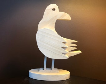 May include: A wooden bird sculpture with a simple design. The bird is standing on a base and has its wings spread out.