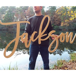 man holding large wood baby name sign 'Jackson'