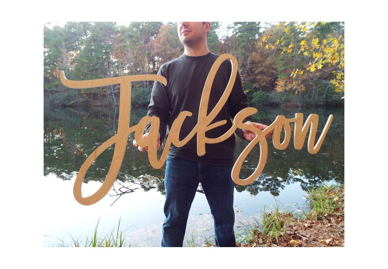 man holding large wood baby name sign 'Jackson'