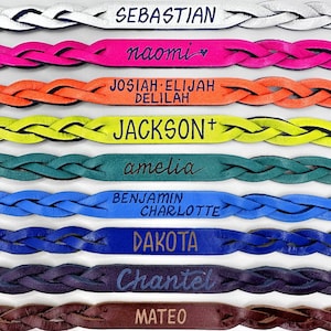 May include: A set of ten braided leather bracelets with different names engraved on them. The bracelets are in various colors, including white, pink, orange, yellow, green, blue, purple, brown, and black.
