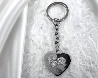 May include: A silver heart-shaped keychain with a photo of a couple engraved on it. The keychain has a silver chain and a silver ring.