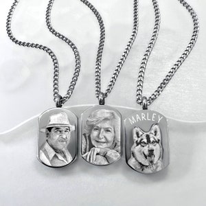 May include: Three stainless steel dog tag necklaces with engraved portraits. One features a man in a hat, another an older woman, and the third a dog with the name "MARLEY". Each tag hangs from a silver chain.