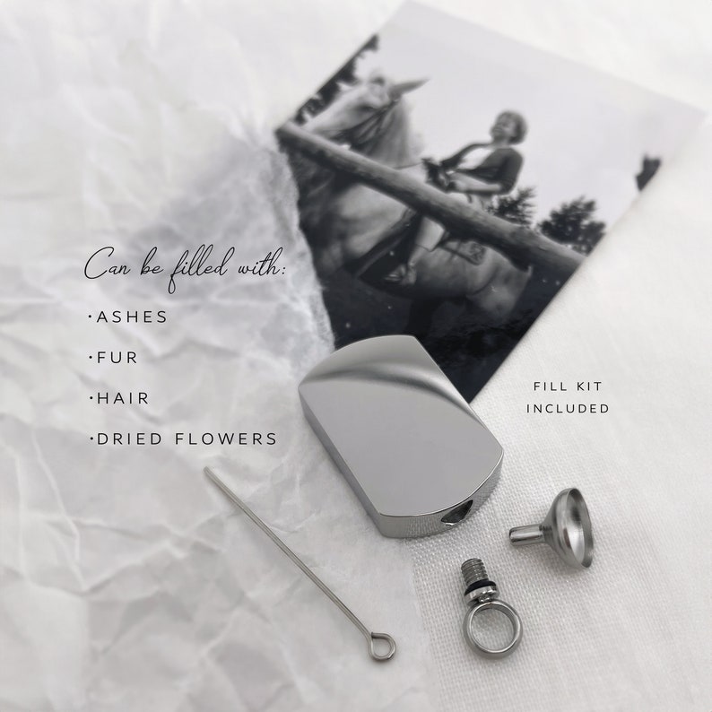 May include: A silver-colored, rectangular cremation urn with a rounded top, a small funnel, and a fill kit. The text "Can be filled with: ASHES, FUR, HAIR, DRIED FLOWERS" is visible. A black and white photo of a person riding a horse is in the background.