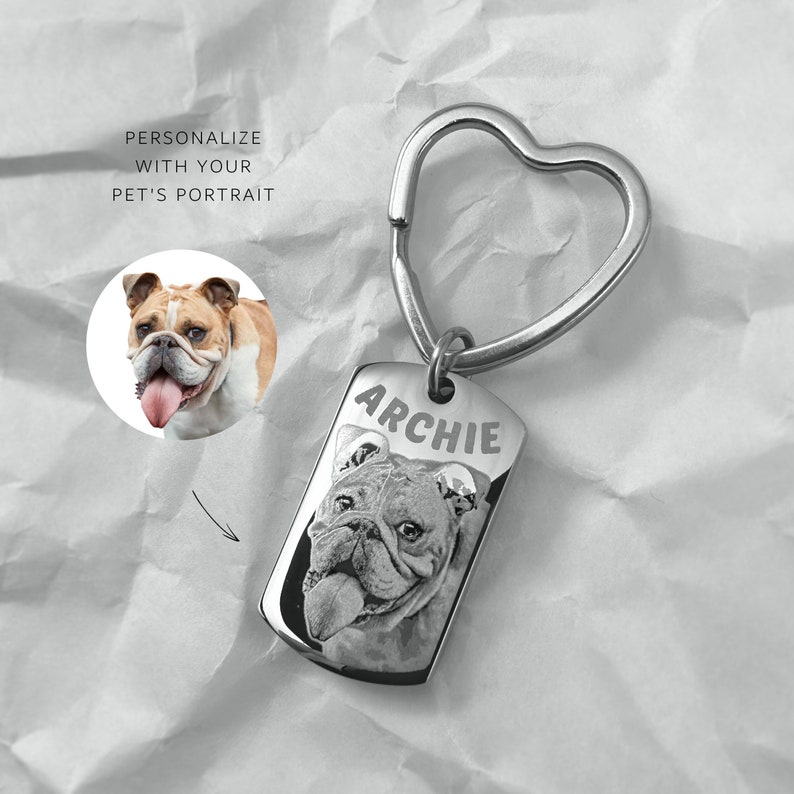 May include: Silver keyring with a heart-shaped ring and a rectangular tag. The tag has the name "Archie" engraved on it and a black and white photo of a bulldog.