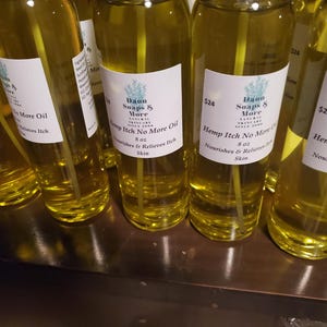 Puede incluir: Varias botellas de vidrio transparente llenas de líquido amarillo, cada una con una etiqueta blanca. Las etiquetas dicen "Dawn Soaps & More" y "Hemp Itch No More Oil." Las botellas son de 237 ml.