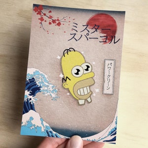 May include: A yellow cartoon character with a large smile and big eyes is depicted on a card with a Japanese wave design. The card has the text "The Simpsons" and "Super Cool" in Japanese.