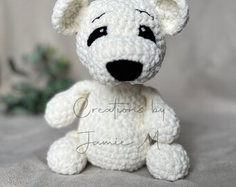 Può includere: Orso polare di peluche bianco lavorato a uncinetto con occhi e naso neri. L'orso è seduto su una superficie bianca. Il testo "Creations by Jamie M" è visibile sul corpo dell'orso.